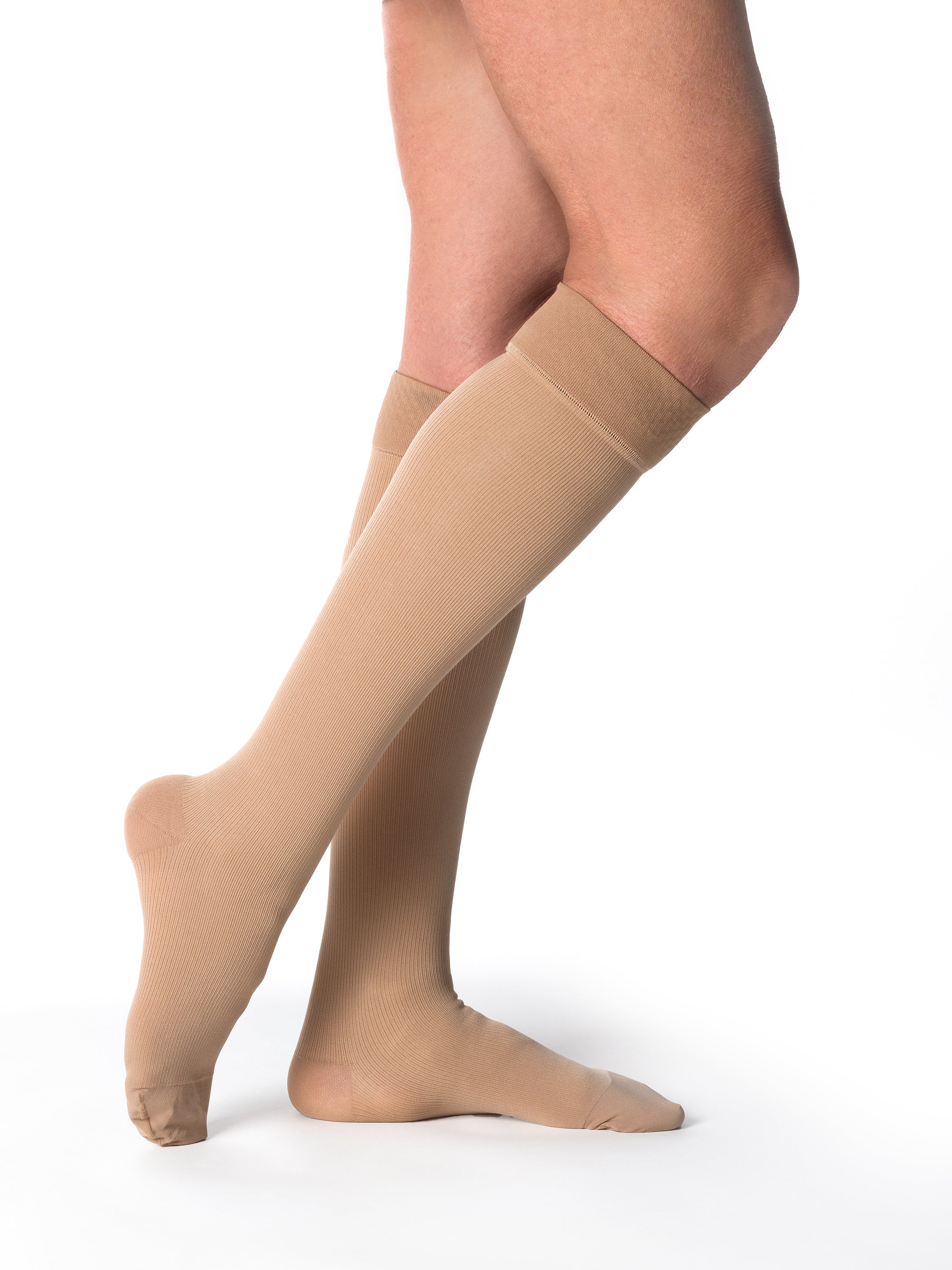 Woman wearing Sigvaris Essential Cotton compression grip-top knee-highs in the color Light Beige