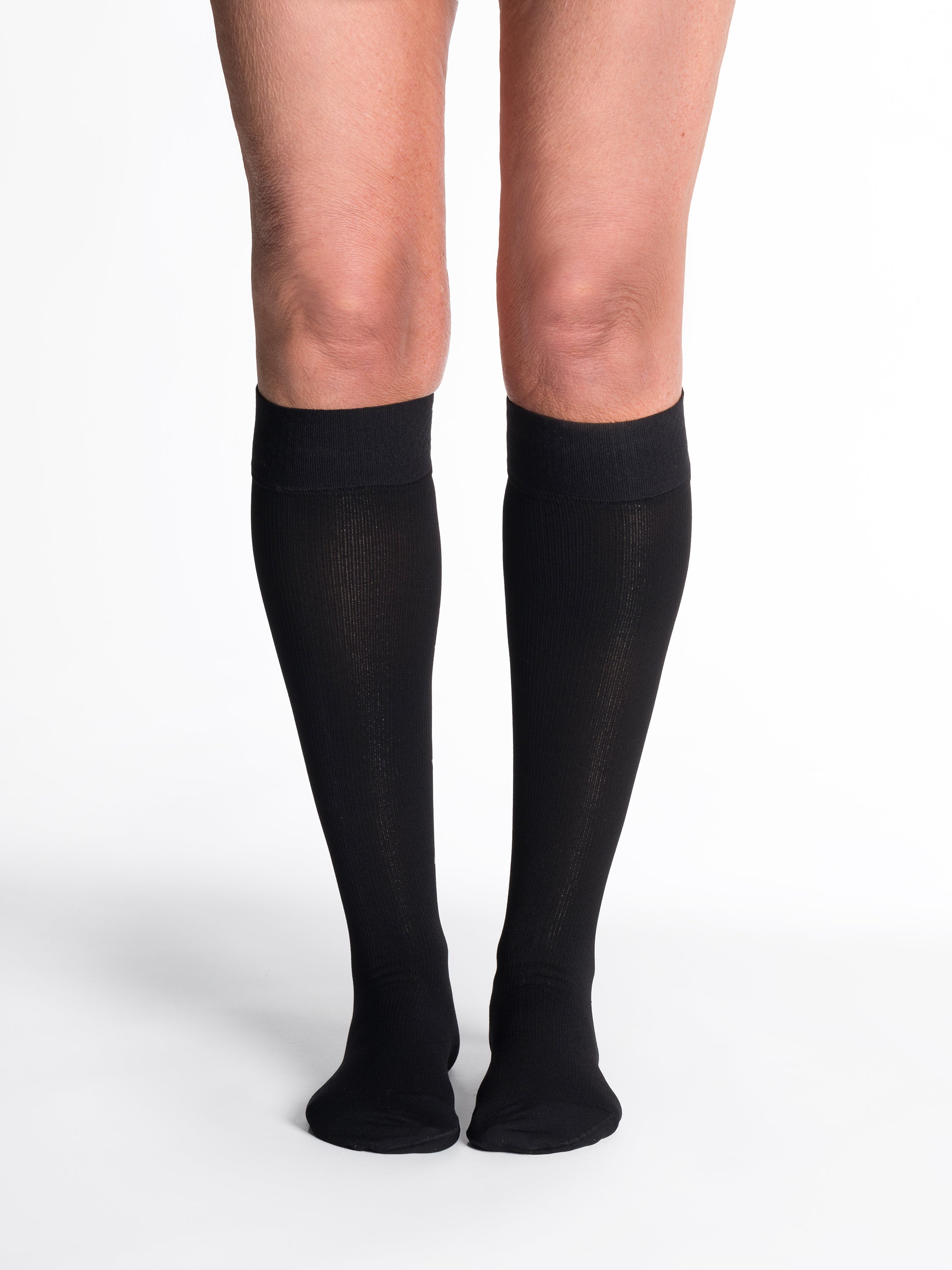 Woman wearing Sigvaris Essential Cotton compression grip-top knee-highs in the color Black