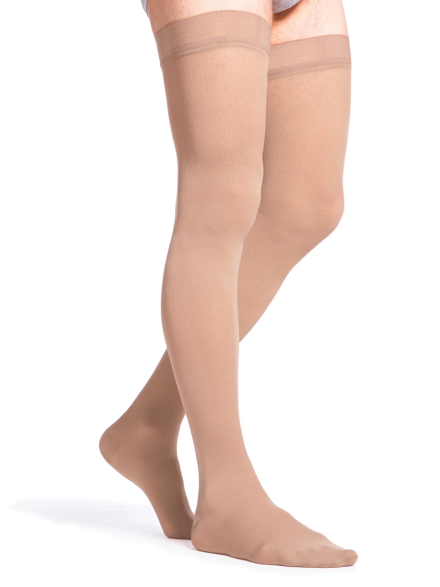 Man wearing Sigvaris Essential Opaque compression thigh-highs in the color Light Beige