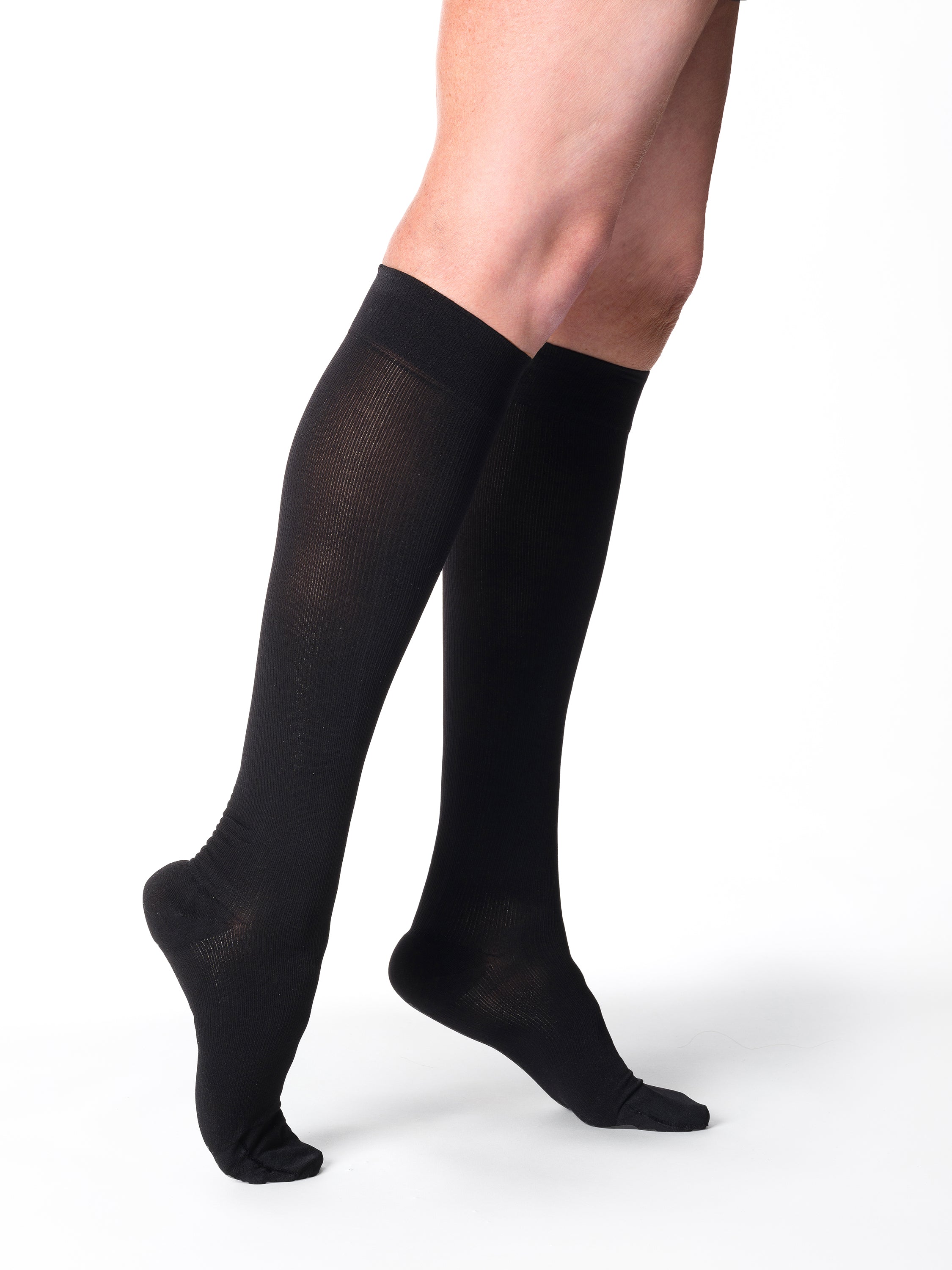 Woman wearing Sigvaris Essential Cotton compression knee-highs in the color Black